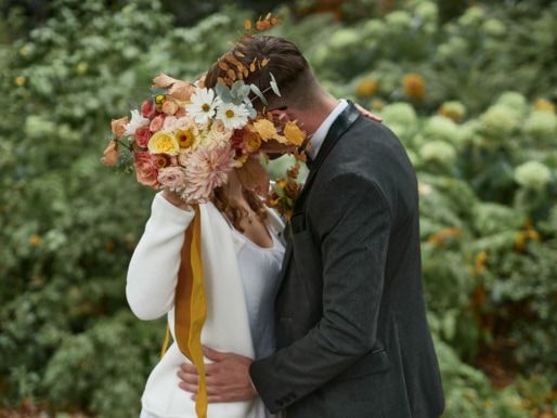 Brautpaar Kuss hinter Blumenstrauß